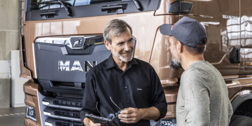 2 Männer vor einem braunen MAN Fahrzeug, ein Kunde und ein Servicemitarbeiter